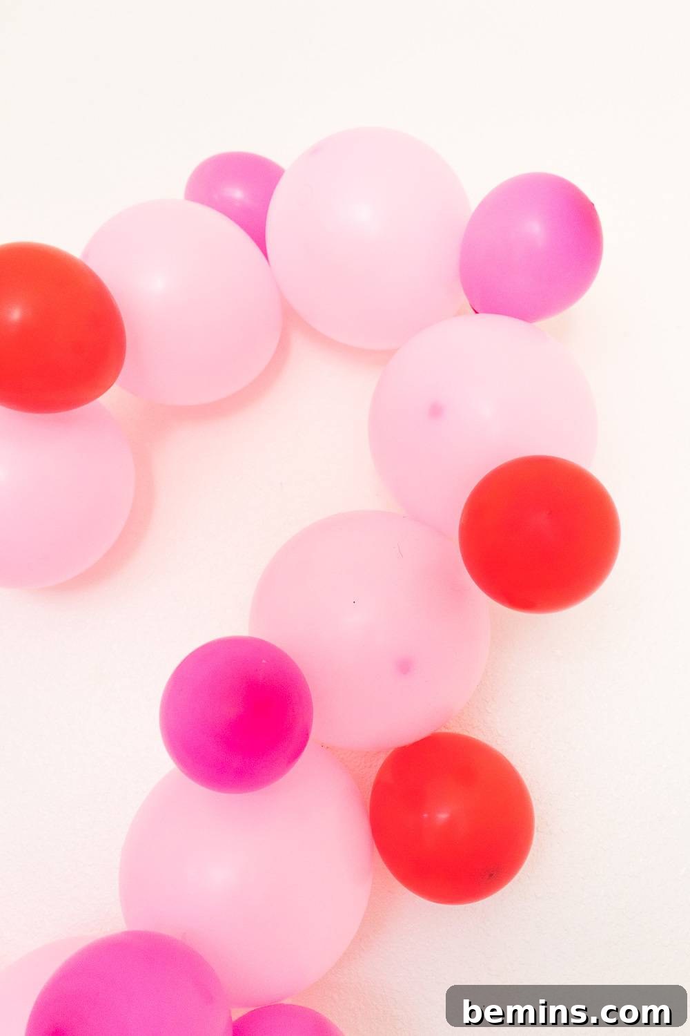 Part of a heart-shaped balloon display featuring pale pink, violet, and red balloons