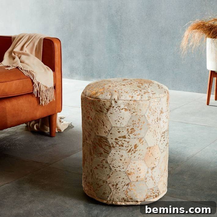 Cowhide pouf with gold hints in front of an orange couch.
