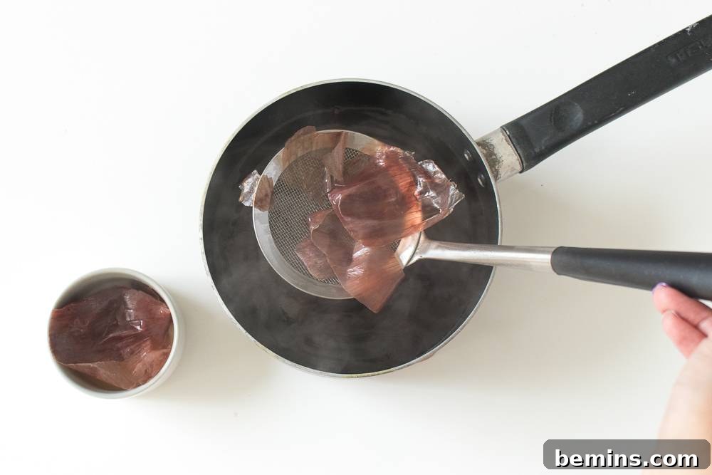 Using a ladle to carefully remove dye materials from a hot pan.