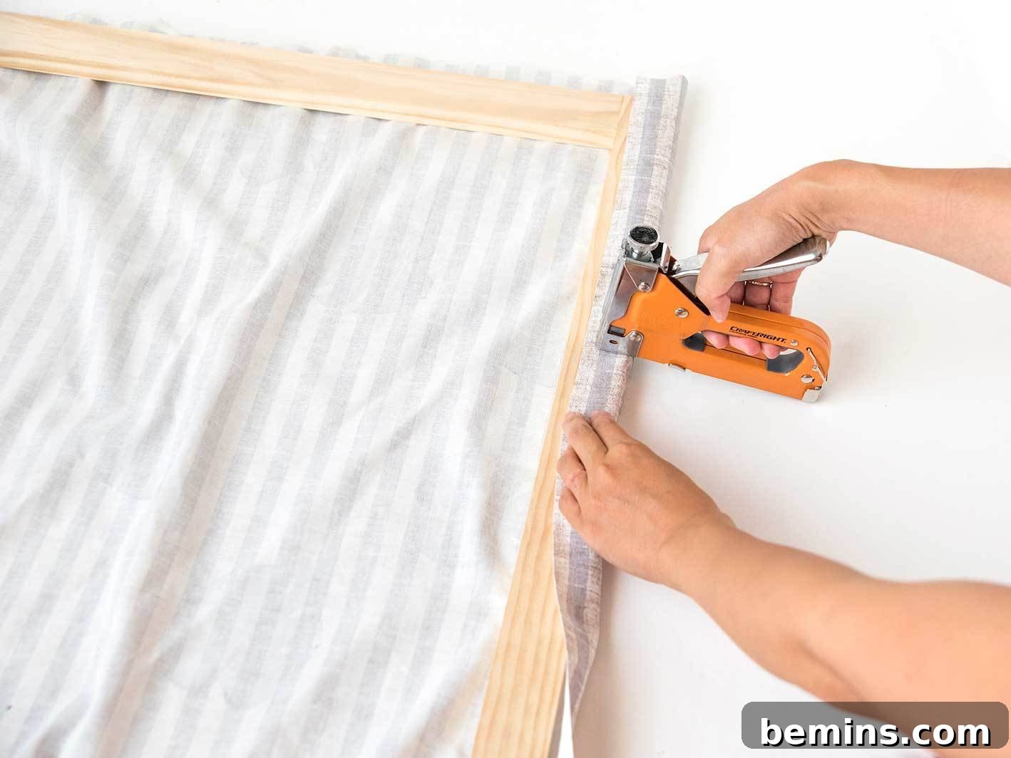Pulling the fabric taut and securing it with staples.
