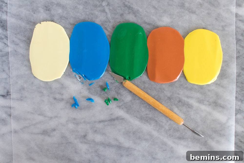 Five vertical ovals of colored clay, one white, one blue, one green, one orange and one yellow above a wooden craft cutter.