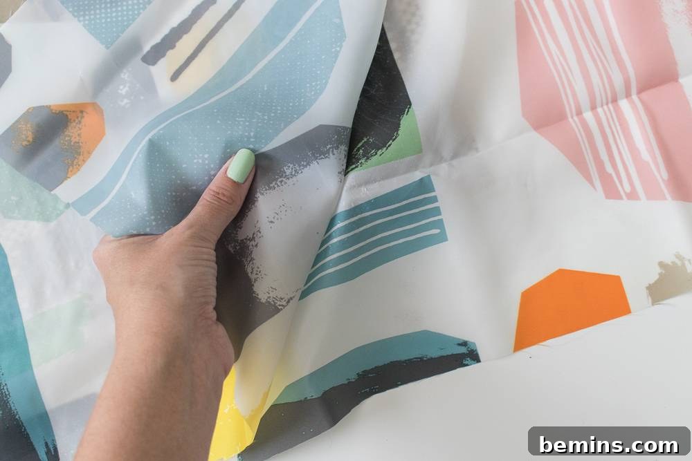 IKEA Shower Curtain Rug DIY: Budget-Friendly Outdoor Decor 7 A hand picking up a piece of colorful wrapping paper, possibly involved in gift-wrapping or a creative DIY project.