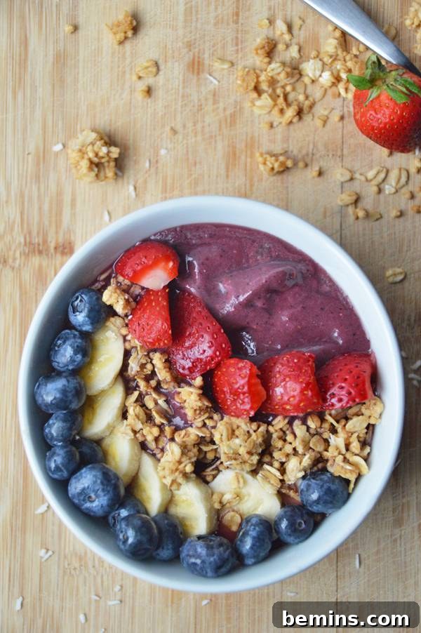 An acai smoothie bowl with strawberries, granola, bananas, and blueberries