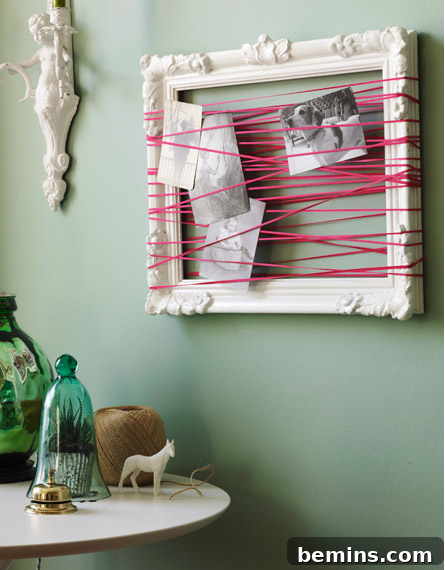 Pink string crosses over a white frame several times, while photos hang in the middle.