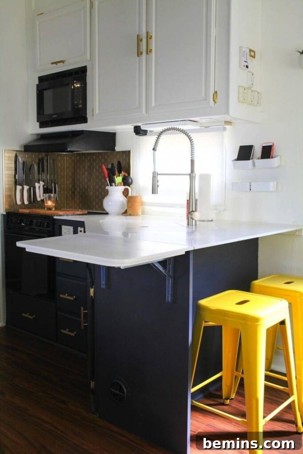 A modern camper kitchen featuring bright yellow barstools, white countertops, and a built-in microwave.