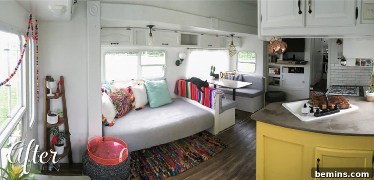The interior of a renovated 5th wheel, featuring a daybed with colorful pillows and a well-designed kitchen nook.