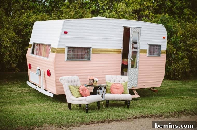 A vintage camper painted in white and pink, with outdoor chairs and a welcoming ambiance.