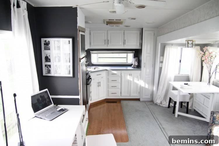 A bright and airy workspace inside a renovated camper, featuring a desk and ample natural light.