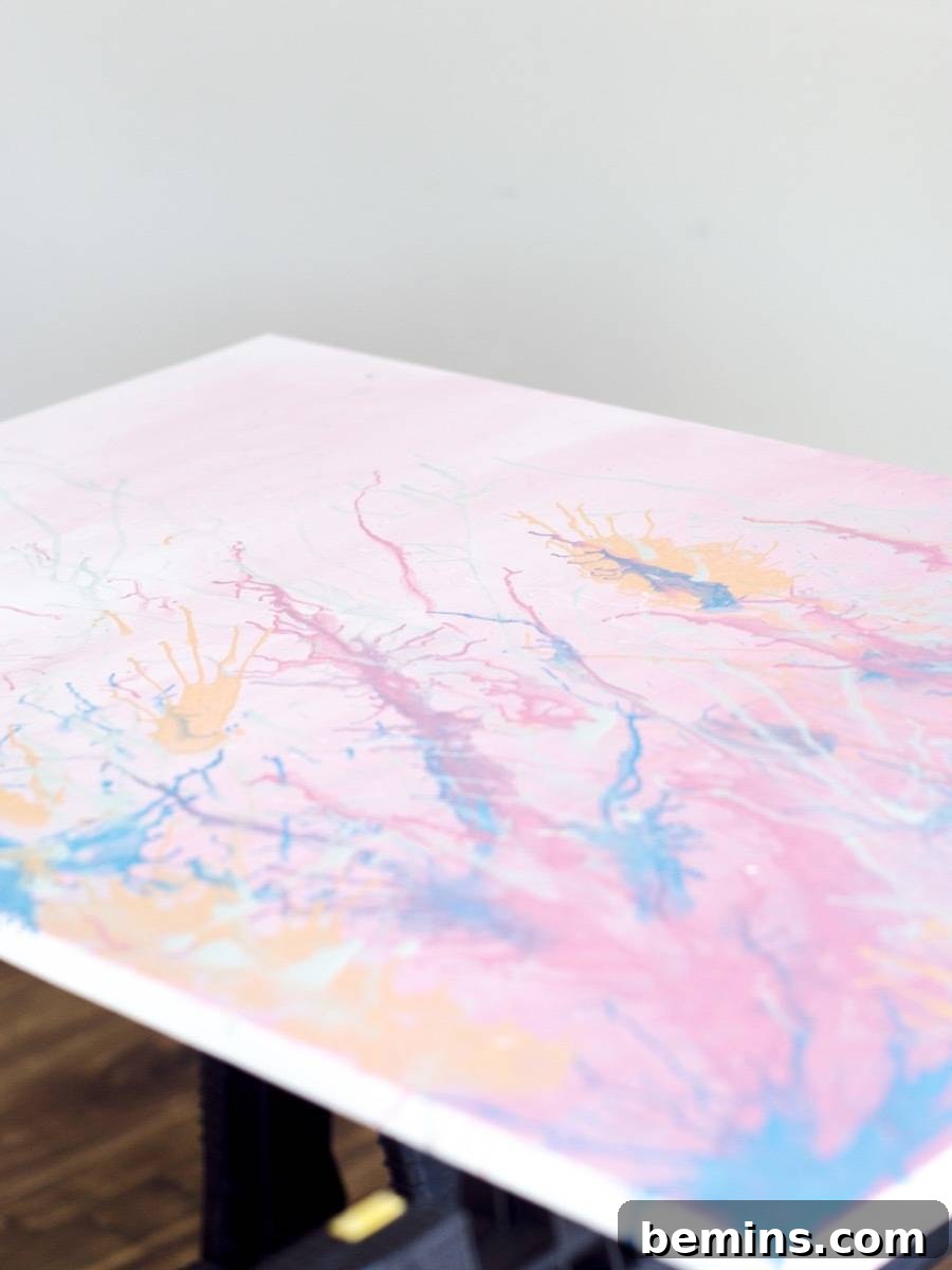 A mostly pink pastel piece of abstract artwork with a white border is laying flat.