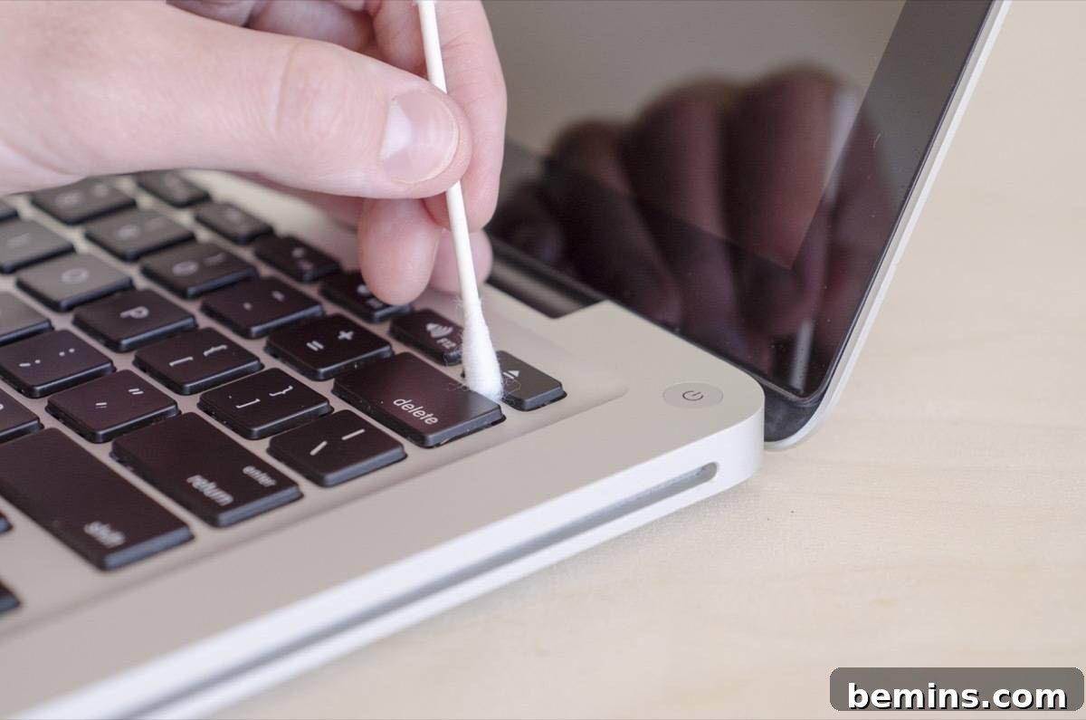 Using a q-tip to clean the crevices of a laptop