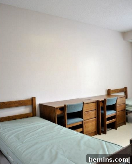 Before: Two wooden table and chairs line in the middle of two single beds.