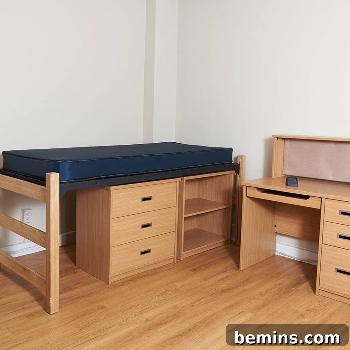 Before: Undecorated dorm room containing a single bed with under-bed storage and a matching desk.