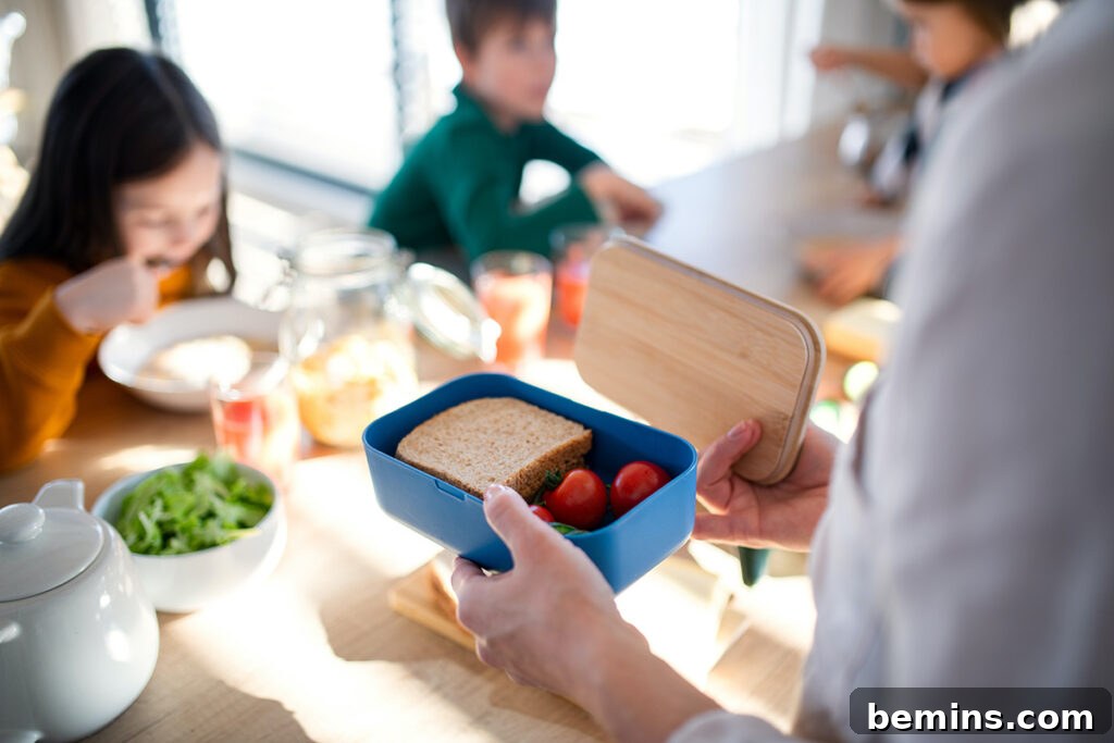 Speedy Lunchbox Solutions for Stress Free Mornings 3 A small, compartmentalized bento box filled with a colorful meal, with children happily playing in the blurred background