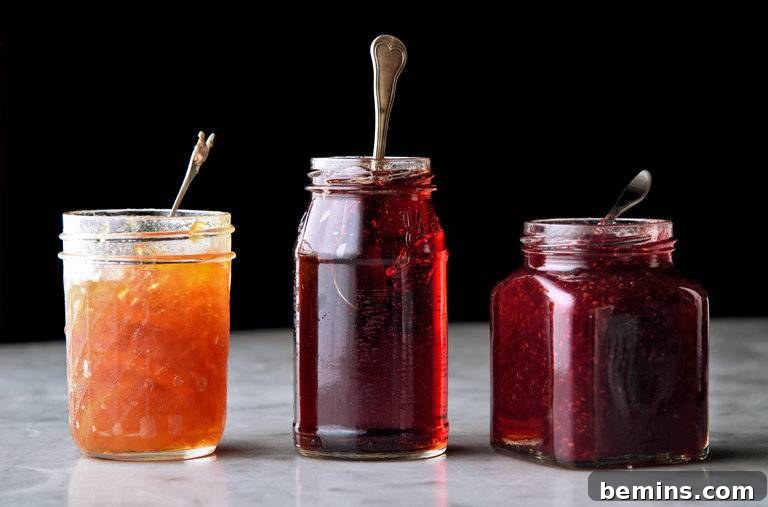 Preserving the Harvest: 10 Winter-Ready Techniques 5 Three open glass jars of homemade jam with spoons, showcasing different fruit flavors.