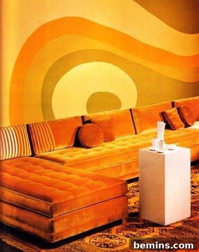 An orange-themed 1970s living room with a wall mural and a sectional sofa.