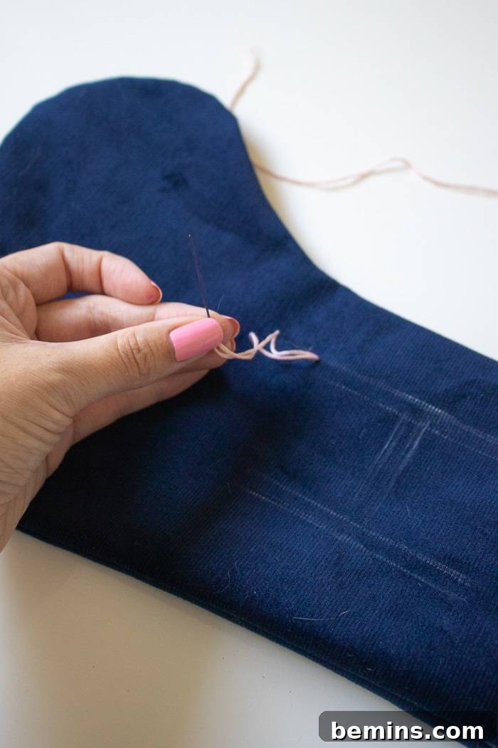 A hand that is sewing blue fabric