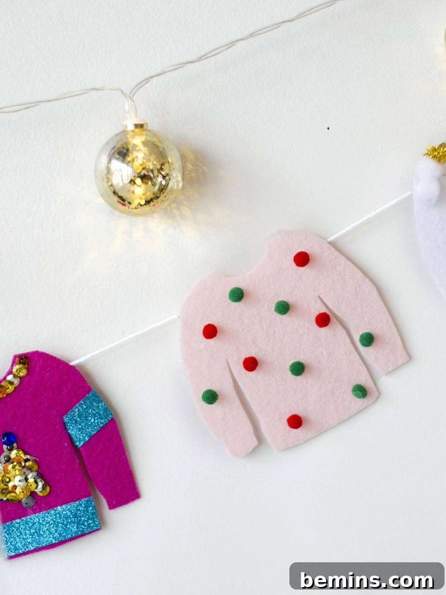 A gold ball on a string above a fuschia and blue sweater and a pink sweater with green and red polka dots on a string.