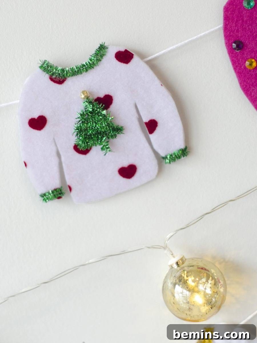 A small christmas sweater lays next to a golden ornament.
