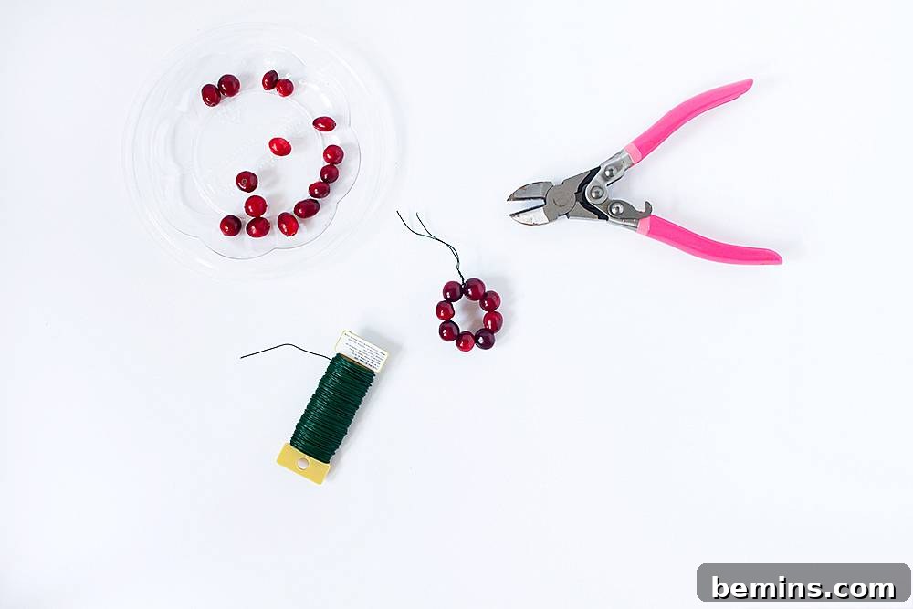 A pair of pink plyers sit on a surface with beads and string.