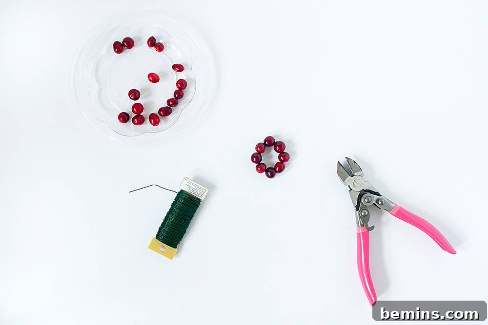 A pair of pink plyers next to beads and wire.