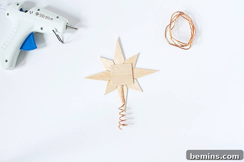 A hot glue gun rests next to some simple Scandinavian style ornaments that are handmade.