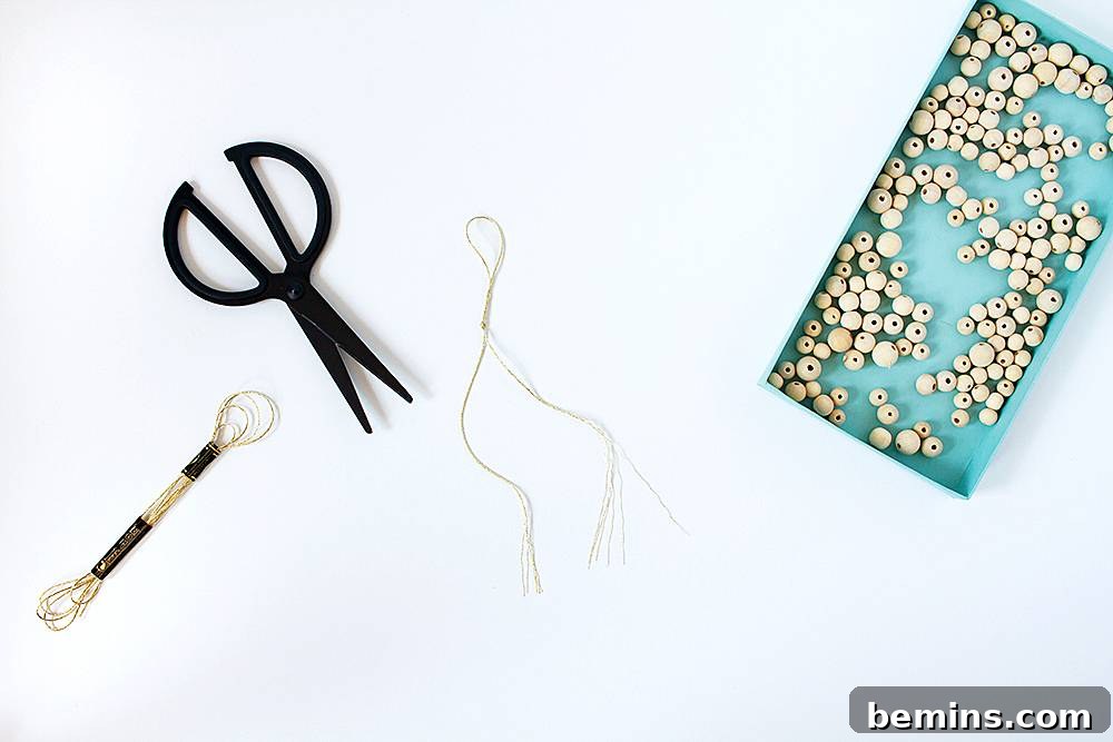 A blue tray holding white beads sits next to a pair of scissors and some thread.