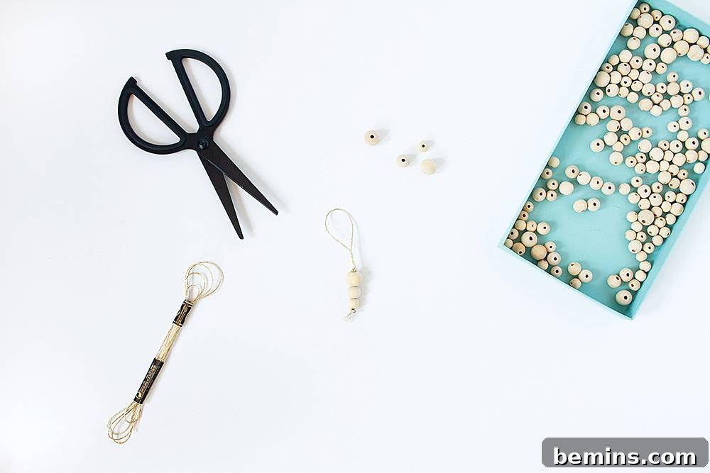 Black scissors are sitting on a surface near other tools and a tray of beads.