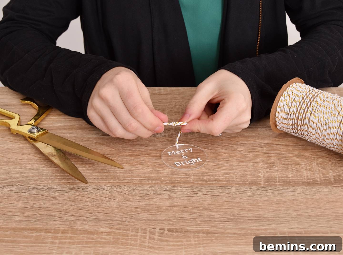 Adding twine to the DIY hand-lettered acrylic ornaments.