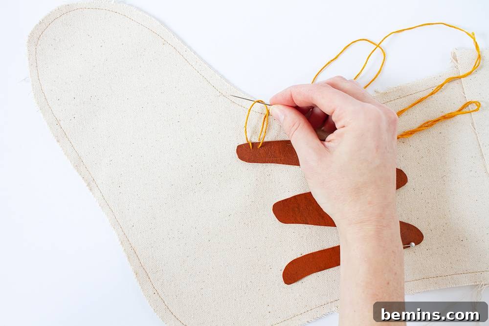 A woman stitches yellow thread through the edge of a holiday stocking.