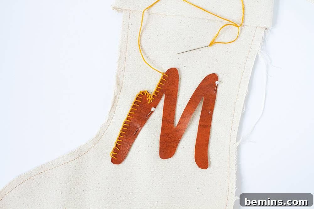 A white stocking with a leather M stitched to it.