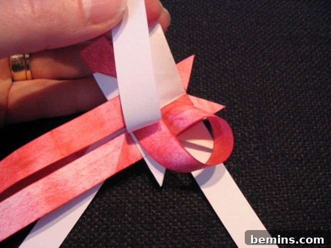 Woman wearing ring and tying pink ribbon. Preparing the strips is essential for forming the final points.