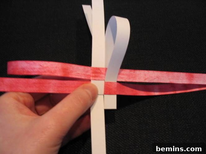 A white and pink paper craft being made. Creating the triangle is the first step in forming a star point.