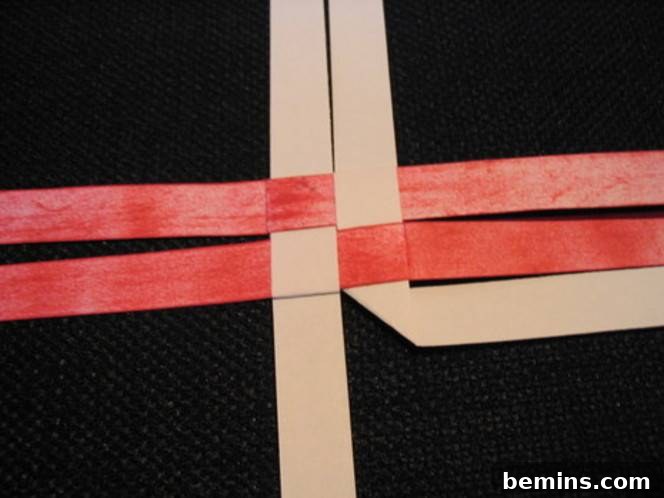 Four strips of brown and red paper weaved together in a basket weave. Looping and creasing adds dimension to the star's points.