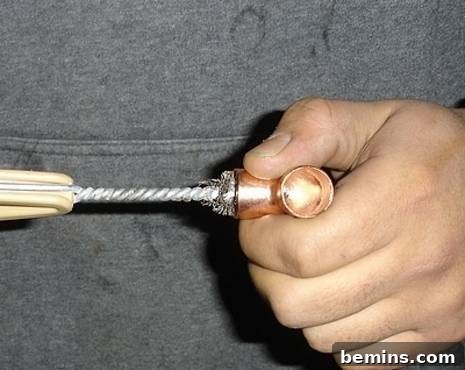 Unleash Your Inner Craftsman: Mastering the Art of Copper Pipe Soldering 5 A person cleaning a copper pipe fitting with a wire brush, highlighting the meticulous cleaning process required for successful soldering.