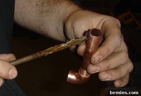 Unleash Your Inner Craftsman: Mastering the Art of Copper Pipe Soldering 6 A person applying flux to a copper pipe, illustrating the importance of proper flux application for a strong solder joint.