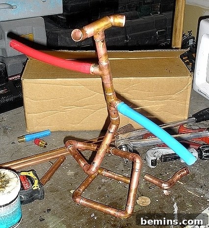 Copper pipe meticulously sculpted into an abstract form, surrounded by smaller copper pieces and plumbing tools on a workbench, showcasing the artistic potential of ordinary materials.