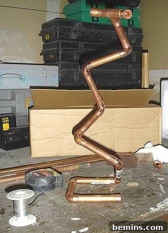 Crafting Copper Art Projects with New Soldering Skills 5 An intricate, zig-zagging copper pipe sculpture takes shape on a work surface, demonstrating a creative and unconventional use of plumbing materials.