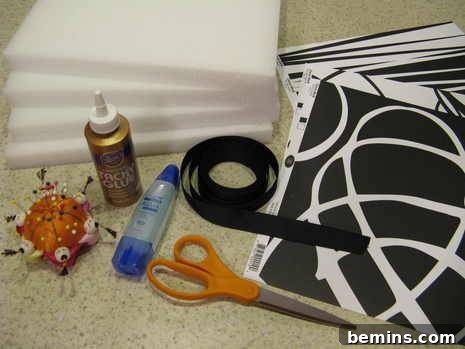 Creating Dimensional Wall Decor from Foam 3 A pin cushion full of pins, a gold tube of glue, a pair of orange handled scissors, four foam boards, some black ribbon and a black and white pattern.