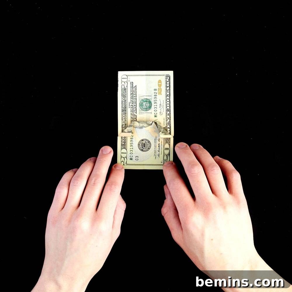 Folding the top corners of the dollar bill down