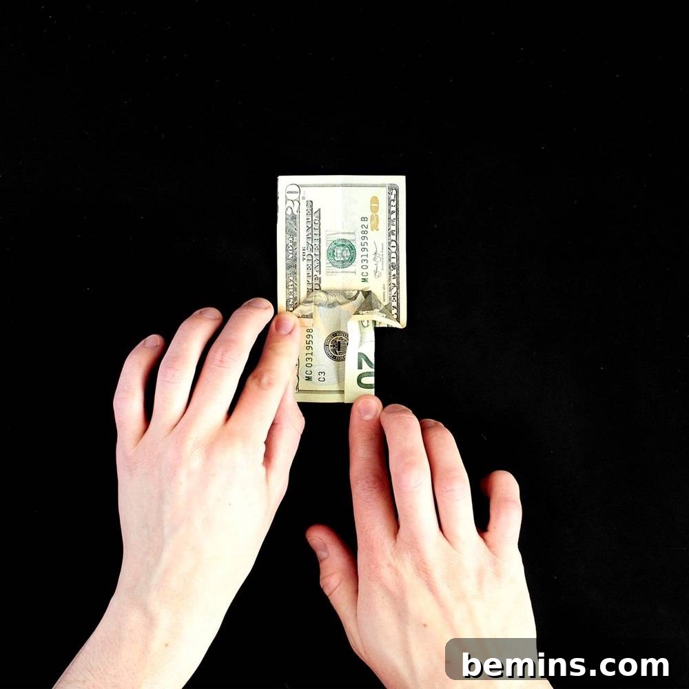 Folding and flattening the bottom corners of the dollar bill