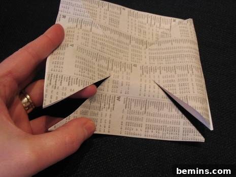 Holding a square strip of paper with diagonal cuts.