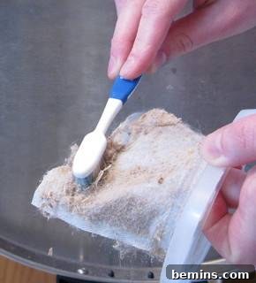 A person scrubbing a vacuum filter with a toothbrush. Demonstrating the proper brushing technique for cleaning a vacuum filter.