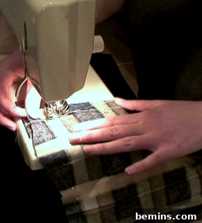 Two hands holding a piece of black and white material through a sewing machine.