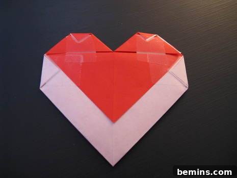 Red origami heart envelope resting on a black table