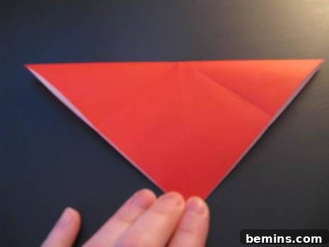Red origami paper being folded to make an envelope