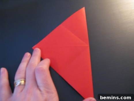 Red paper folded in half, held by a hand with a ring