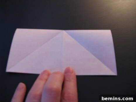 Man folding white paper to make an origami heart envelope