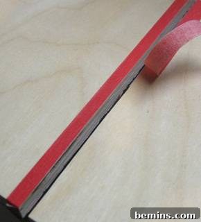 Preventing Plywood Splintering: A Guide to Clean Cuts 4 Masking tape being peeled away from a cleanly cut plywood edge.
