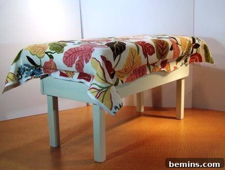 The fabric is being meticulously stapled to the bench frame.