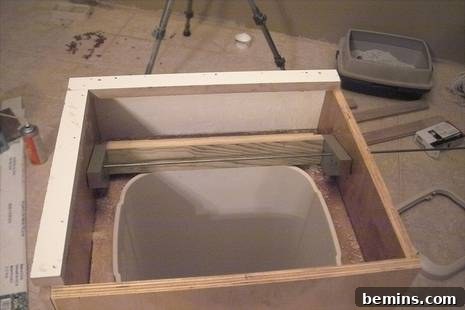 Discreet Waste Solutions 4 A close-up view of the custom trash can cabinet's interior, showing the plastic bin insert and the fiberglass resin-sealed plywood, emphasizing its clean and durable design.